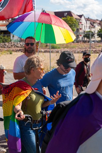 CSD Rahtenow Menschen mit bunten Fahnen und Regenschirmen