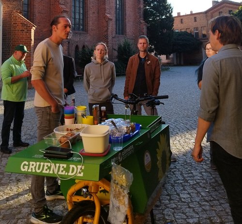 2. Demokratie-Picknick Dr. Michael Wiebersinsky und Heiko Knopf und weitere Personen stehen auf dem Platz vor der Kirche und unterhalten sich