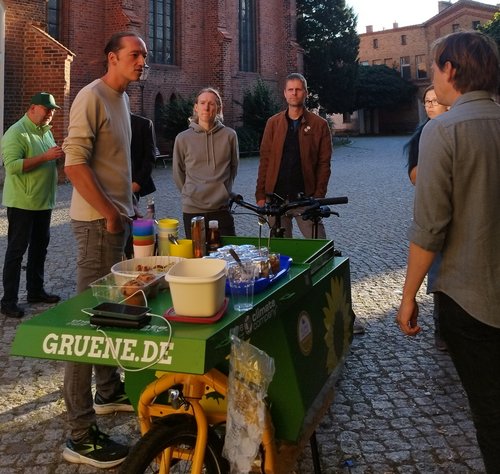 2. Demokratie-Picknick Dr. Michael Wiebersinsky und Heiko Knopf und weitere Personen stehen auf dem Platz vor der Kirche und unterhalten sich