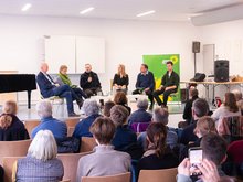 Menschen bei einer Diskussionsveranstaltung, Blick aus dem Publikum auf das Podium