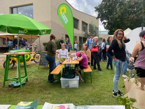 Grüner Stand auf dem Stadtfest mit Menschen, die diskutieren