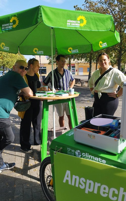 Grüner Stand mit Menschen im Gespräch und Lastenfahrrad